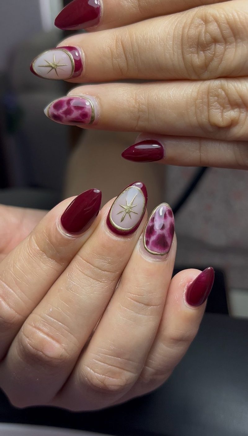 Nail art en tonos borgoña con detalles dorados
